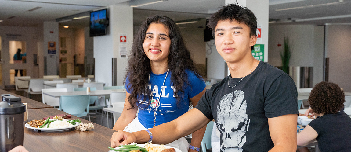 Two students sitting in dining hall with food