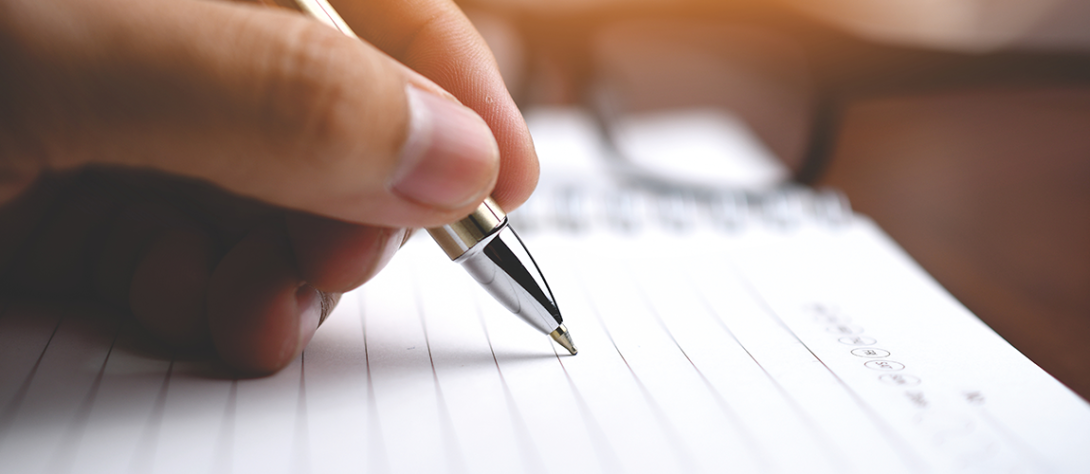 A hand writting on a piece of paper with a pen